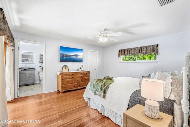 bedroom featuring connected bathroom, hardwood / wood-style floors, and ceiling fan