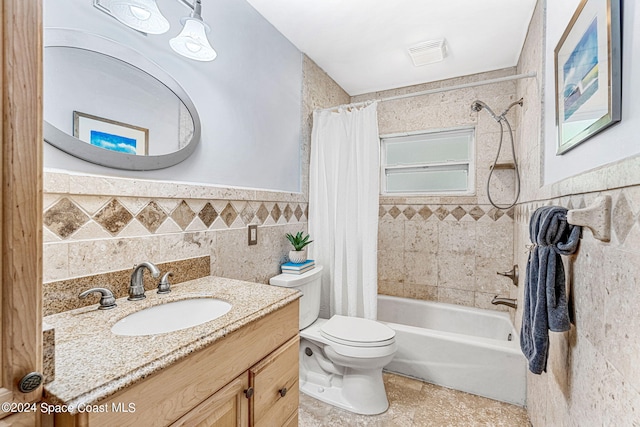 full bathroom featuring toilet, shower / tub combo with curtain, vanity, and tile walls