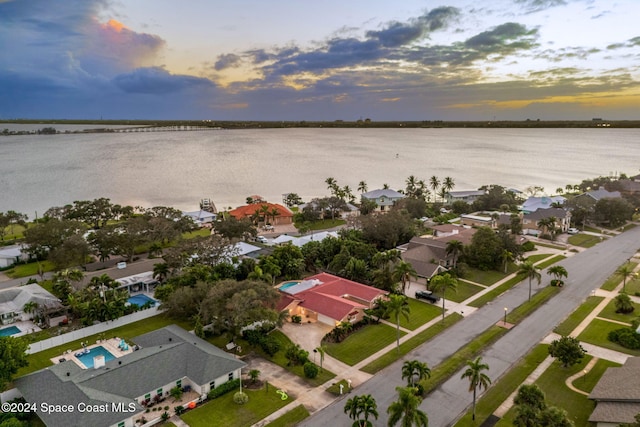 aerial view at dusk featuring a water view