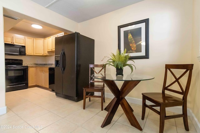 kitchen featuring black appliances, light brown cabinets, light countertops, light tile patterned floors, and baseboards