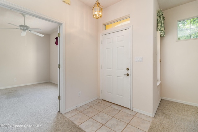 foyer with light colored carpet and ceiling fan with notable chandelier