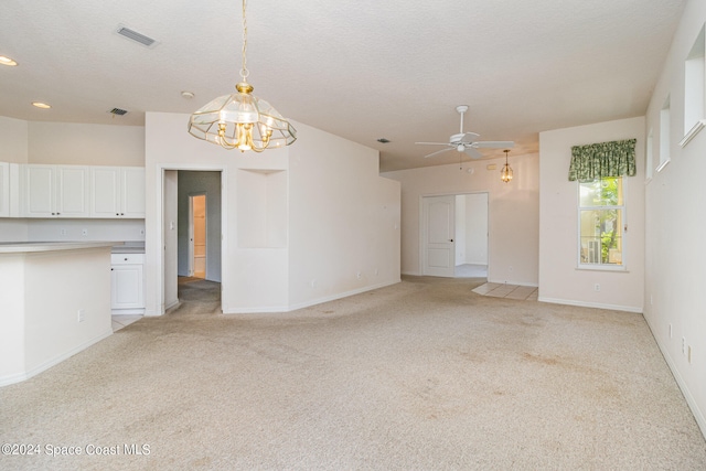 interior space with a textured ceiling, light colored carpet, and ceiling fan with notable chandelier