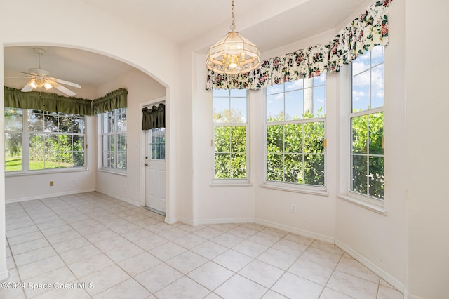 unfurnished sunroom with ceiling fan with notable chandelier and a wealth of natural light