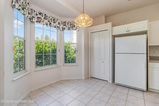 unfurnished dining area featuring light tile patterned flooring, a chandelier, and plenty of natural light