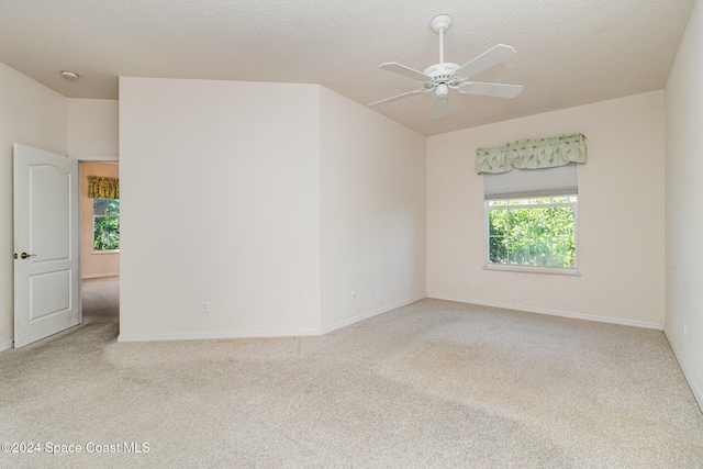 carpeted empty room featuring a textured ceiling, plenty of natural light, and ceiling fan