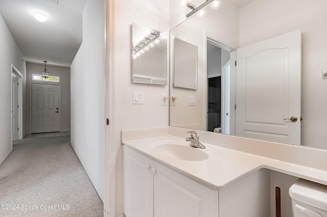 bathroom with vanity, toilet, and a textured ceiling