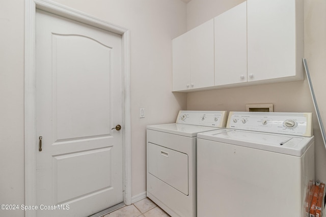 laundry room featuring light tile patterned floors, cabinets, and separate washer and dryer