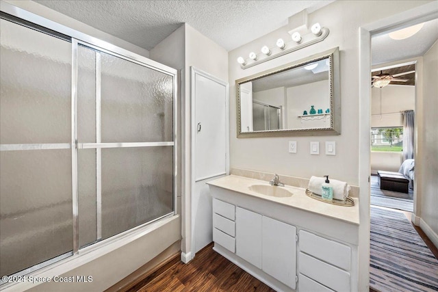 bathroom featuring hardwood / wood-style floors, vanity, a shower with shower door, and a textured ceiling