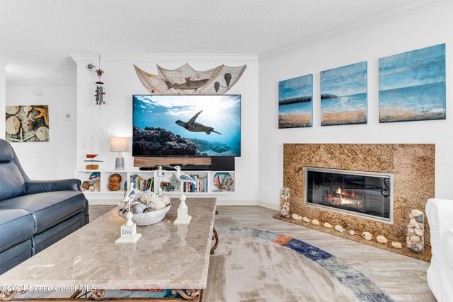 living room featuring crown molding, a fireplace, wood-type flooring, and a textured ceiling