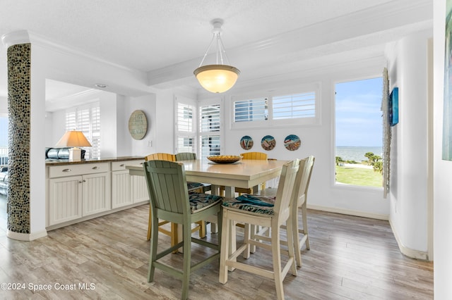 dining room featuring a textured ceiling, light wood-type flooring, ornamental molding, and a wealth of natural light