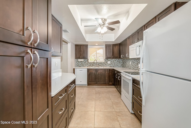 kitchen with decorative backsplash, light tile patterned floors, a raised ceiling, white appliances, and ceiling fan