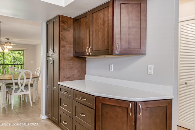 kitchen with dark brown cabinetry, light tile patterned flooring, and ceiling fan