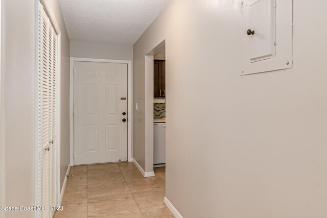 hallway with a textured ceiling and light tile patterned floors