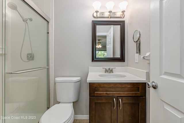 bathroom with vanity, a shower with shower door, toilet, and ceiling fan