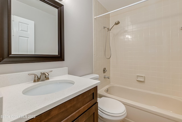 full bathroom featuring vanity, tiled shower / bath combo, and toilet