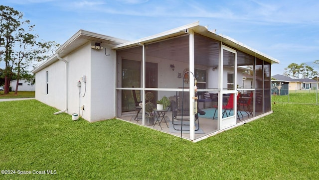 rear view of property with a sunroom, a yard, and a patio