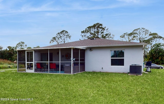 rear view of house featuring a sunroom, central air condition unit, and a lawn