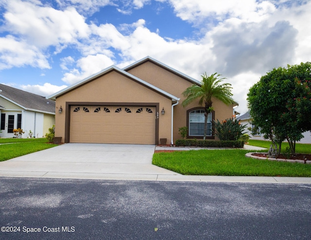 ranch-style house with a front yard, driveway, an attached garage, and stucco siding