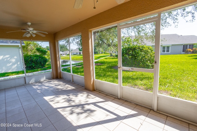 unfurnished sunroom featuring ceiling fan and a water view