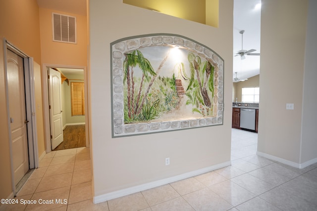 hallway featuring high vaulted ceiling and light tile patterned flooring