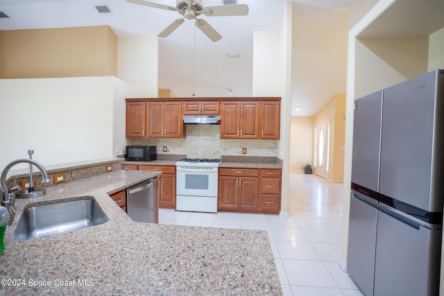 kitchen with a towering ceiling, sink, appliances with stainless steel finishes, and tasteful backsplash