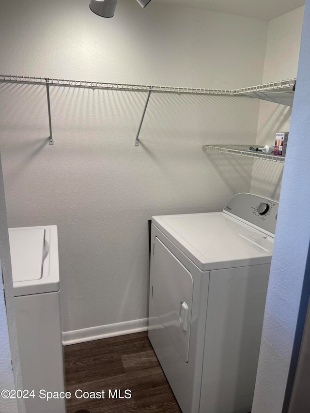 clothes washing area featuring dark wood-type flooring and washing machine and dryer