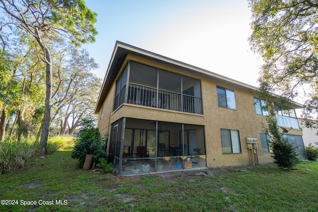 rear view of property featuring a yard and a sunroom