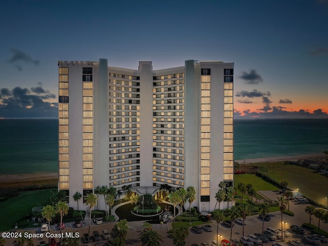 outdoor building at dusk featuring a water view and a view of the beach