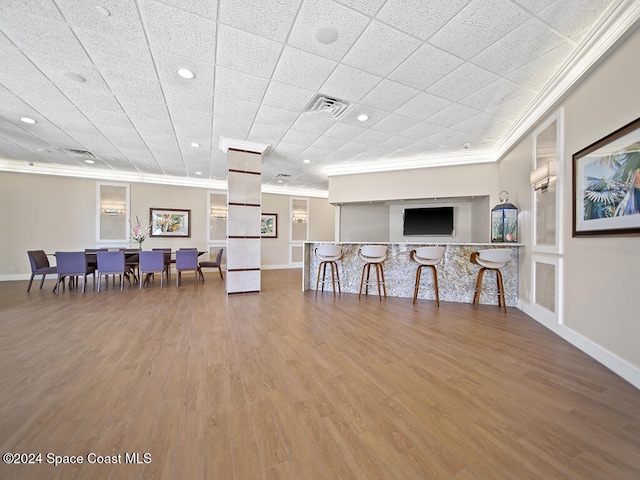 interior space with crown molding, bar, and hardwood / wood-style flooring