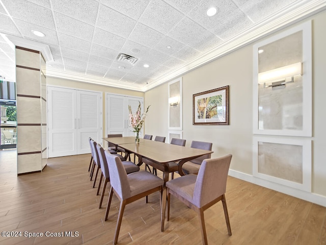 dining space featuring a paneled ceiling, ornamental molding, and light wood-type flooring