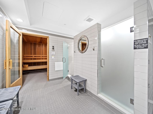 bathroom with an enclosed shower, tile walls, and tile patterned flooring