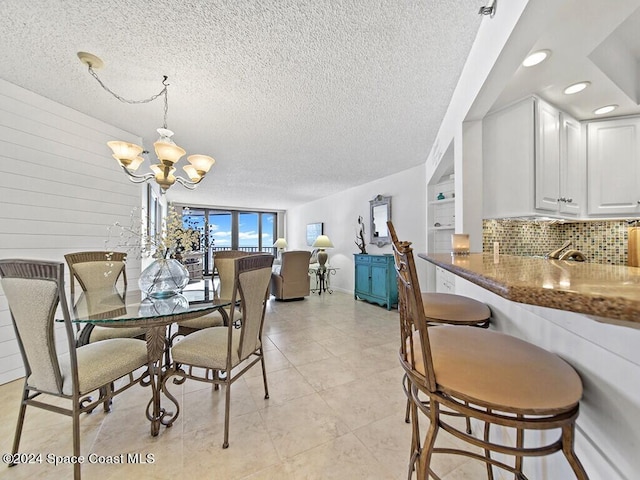 tiled dining area featuring a textured ceiling and an inviting chandelier