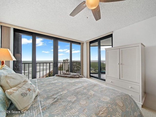 bedroom with expansive windows, multiple windows, access to exterior, and ceiling fan