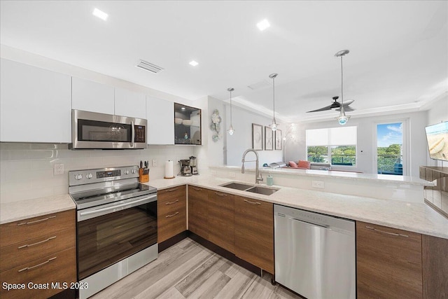 202 Ivory Coral Ln Unit 405, Merritt Island, FL 32953 - kitchen featuring appliances with stainless steel finishes, a sink, a peninsula, light wood-style floors, and tasteful backsplash