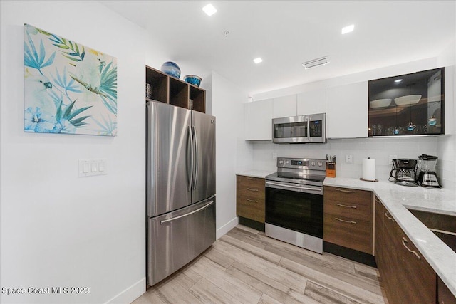 202 Ivory Coral Ln Unit 405, Merritt Island, FL 32953 - kitchen featuring stainless steel appliances, tasteful backsplash, light wood-style floors, dark brown cabinets, and baseboards