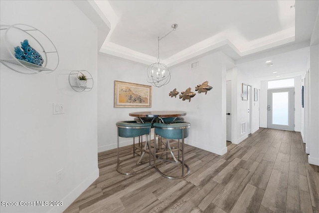 interior space with hardwood / wood-style flooring, an inviting chandelier, and a raised ceiling