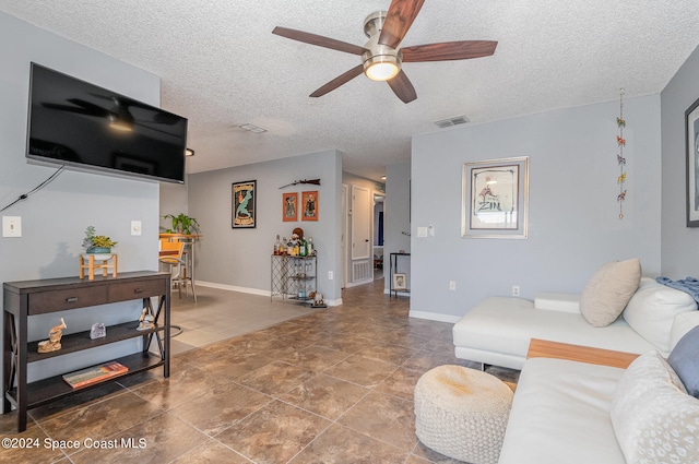 tiled living room with a textured ceiling and ceiling fan