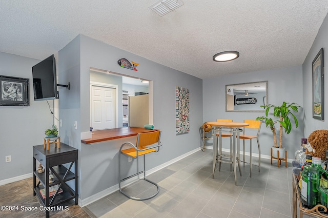 tiled dining room with a textured ceiling