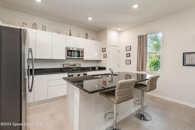 kitchen with white cabinetry, appliances with stainless steel finishes, sink, and an island with sink