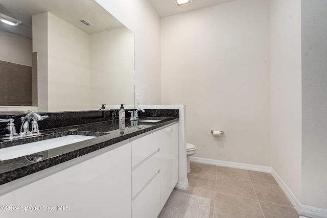 bathroom with toilet, vanity, and tile patterned floors