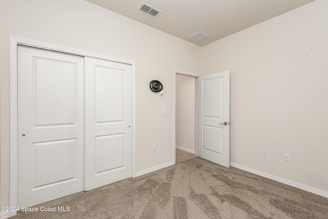 unfurnished bedroom featuring a textured ceiling, carpet floors, and a closet