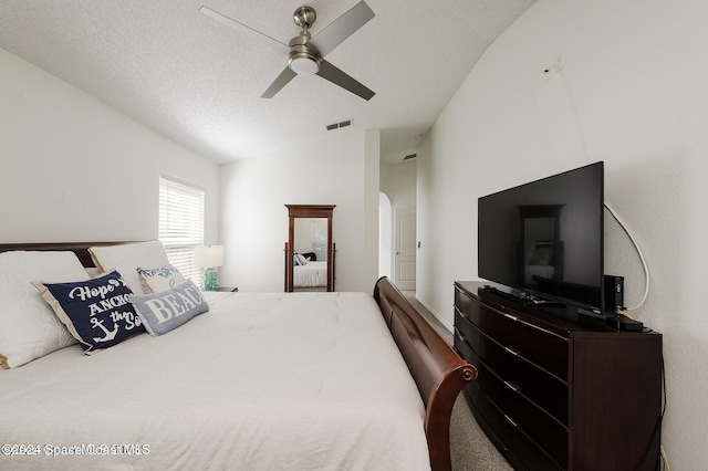 bedroom with vaulted ceiling, a textured ceiling, and ceiling fan