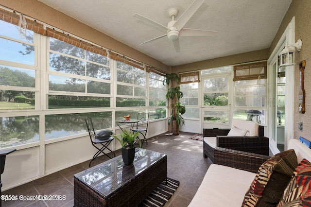 sunroom featuring a water view and ceiling fan