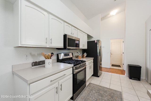 kitchen with appliances with stainless steel finishes, white cabinetry, and light tile patterned floors