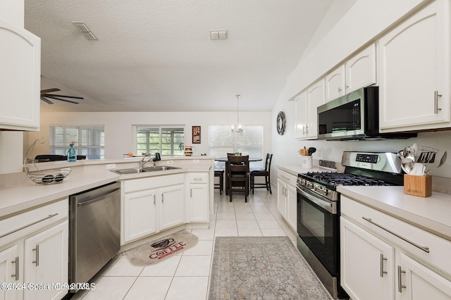 kitchen featuring sink, ceiling fan with notable chandelier, a textured ceiling, stainless steel appliances, and pendant lighting