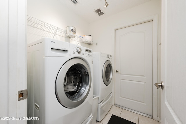 laundry area with independent washer and dryer and light tile patterned floors