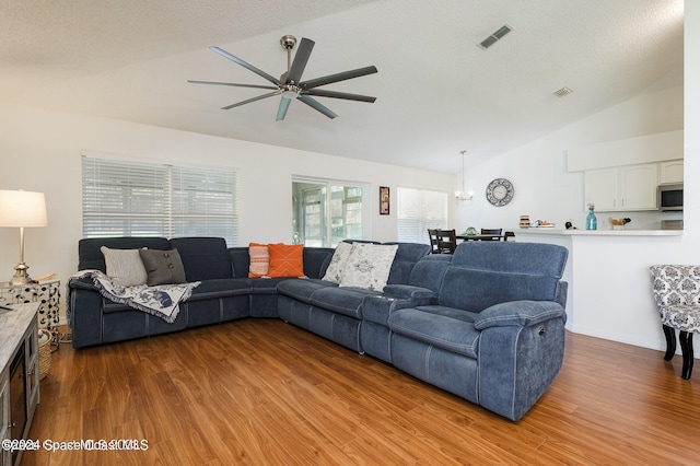 living room featuring lofted ceiling, a textured ceiling, light wood-type flooring, and ceiling fan