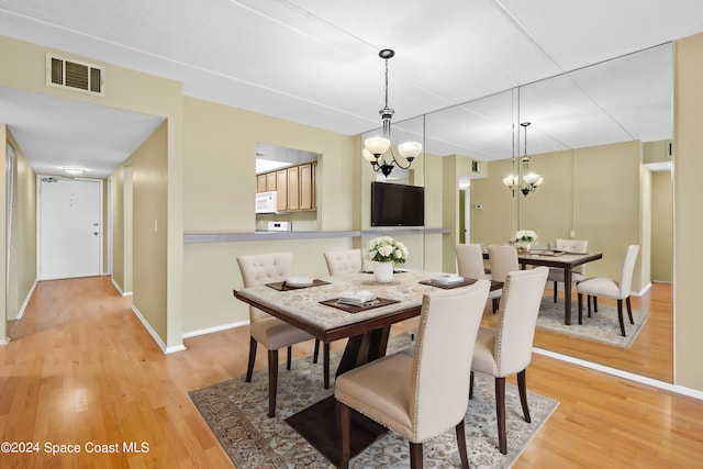 dining room with light wood-type flooring and a notable chandelier