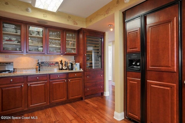 kitchen featuring hardwood / wood-style floors, decorative backsplash, and light stone countertops