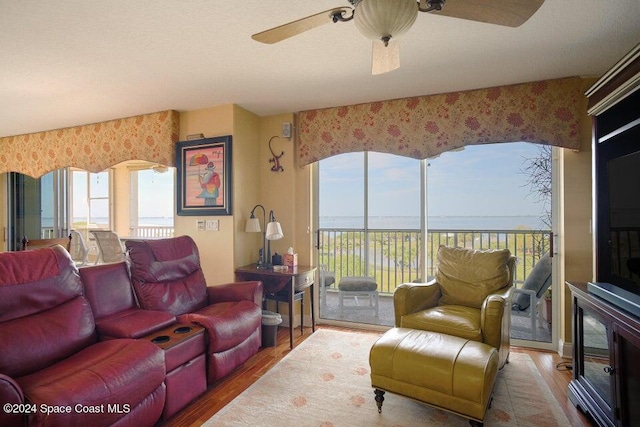 living room with hardwood / wood-style flooring, ceiling fan, and a water view